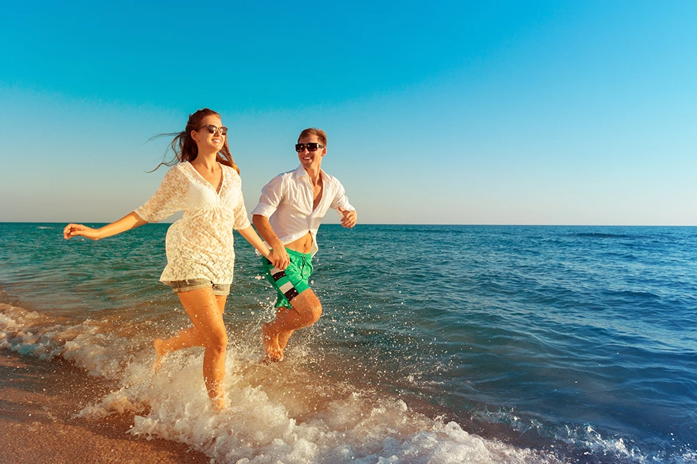 Happy Couple in Manhattan Beach California Running in the ocean after Virtual Therapy Session with Aetna for relationships