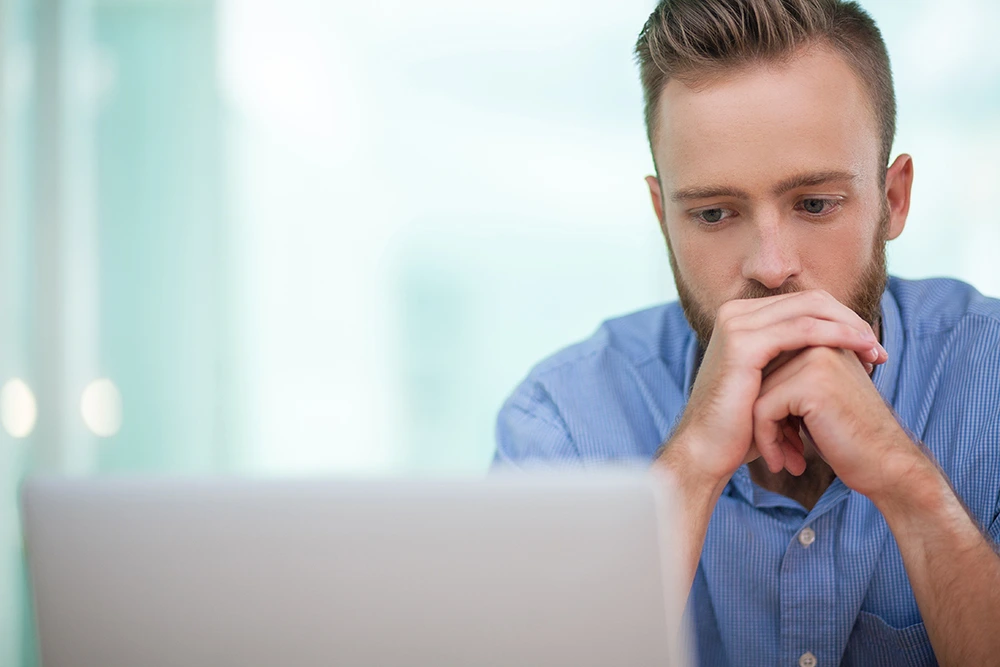 a serious moment during online therapy session for depression with a man wearing a denim shirt
